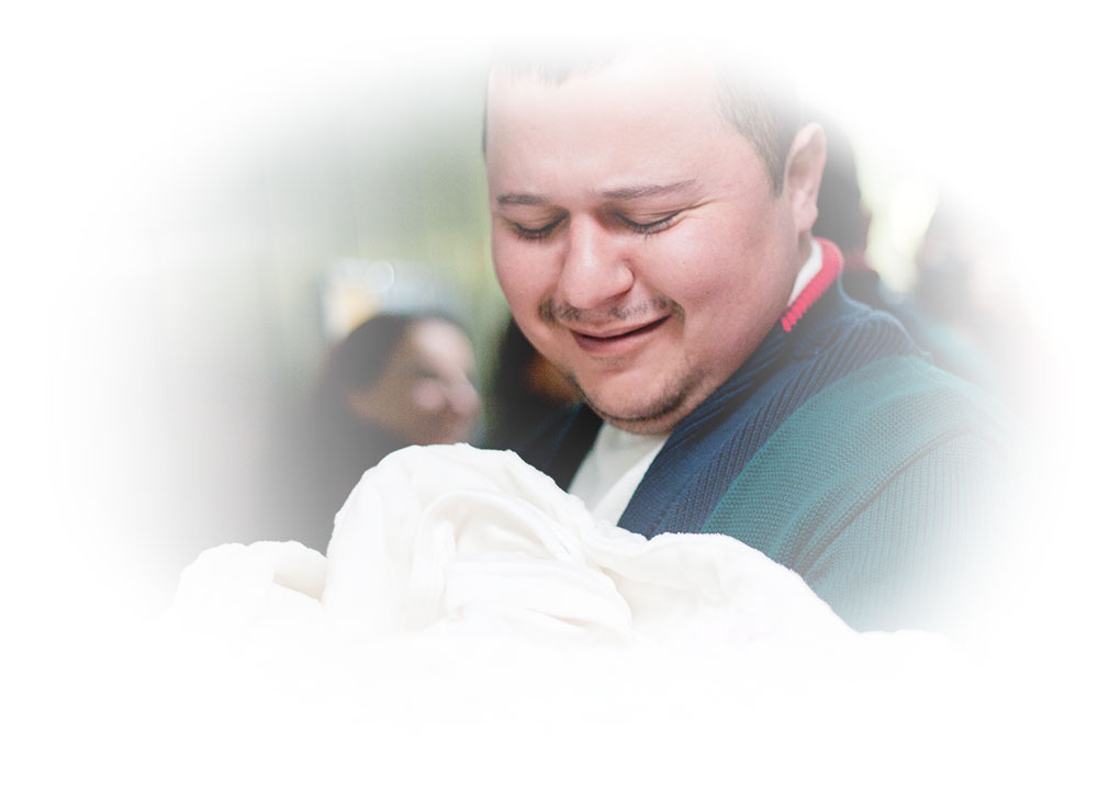 new father looking at his newborn baby bundled in a blanket
