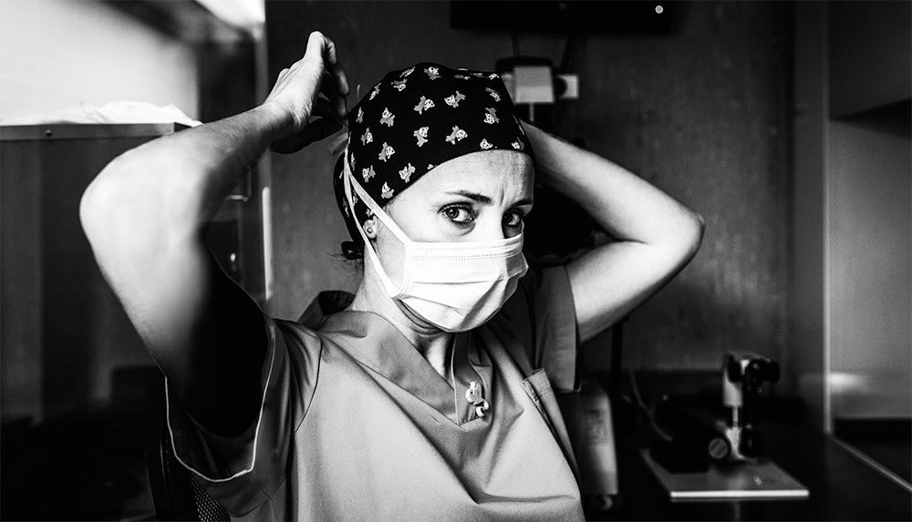 serious-looking nurse putting a bandana on as she prepares for surgery