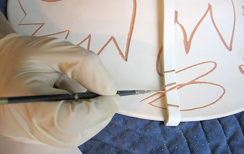 Gloved hand detailing a piece of artwork