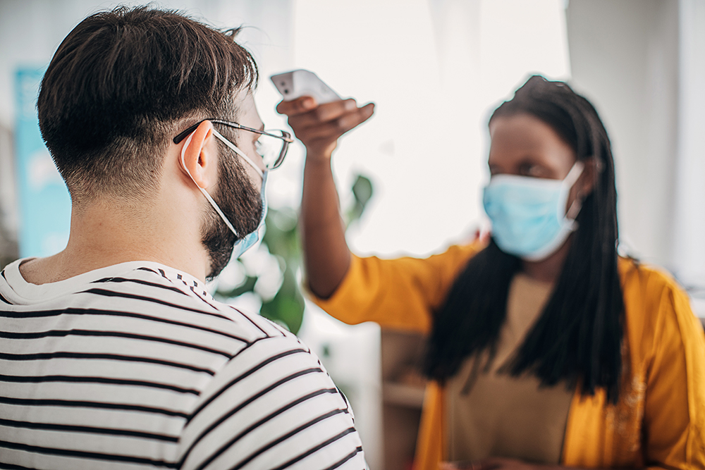 Woman taking man's temperature at a healthcare facility