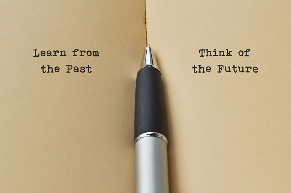 Learn from the past ... think of the future; pen in the middle of two pieces of paper