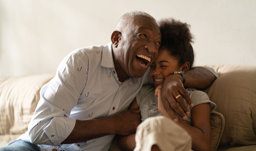 elderly man and young girl embracing and laughing