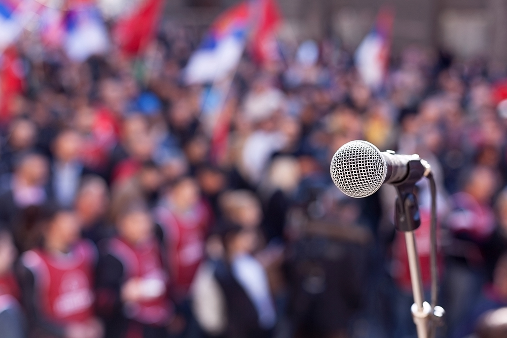 microphone and stand in front of a large group of people