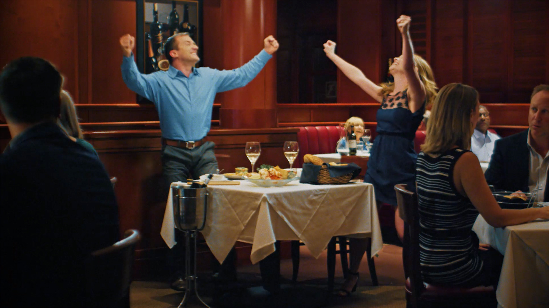 Young couple standing up and celebrating at a fancy restaurant