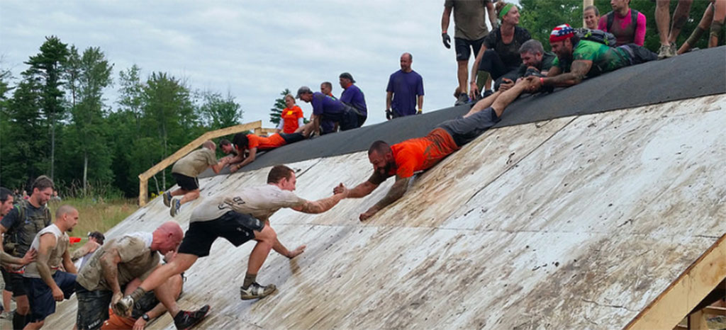 Team members climbing a wall during a Tough Mudders competition